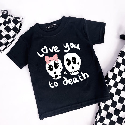 Kids black tee shirt with "Love you to death" printed on and 2 skulls, one with a pink ribbon