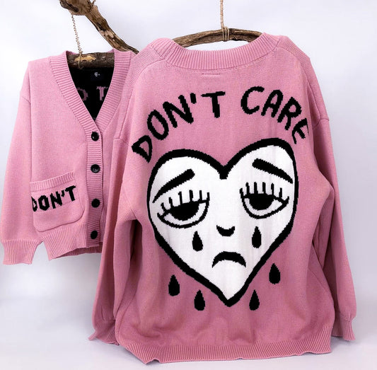 Pink knitted cardigan with "Don't Care" printed on and crying heart face
