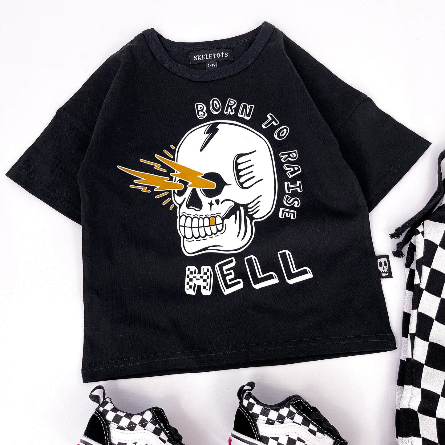 Kids black t shirt with "born to raise hell" printed on and a design of a skull shooting lightning bolts from its eye sockets