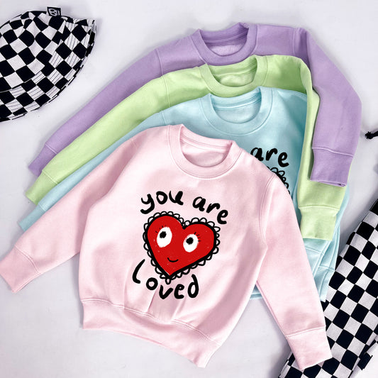 Kids pastel pink sweatshirt with heart and "you are loved" printed on