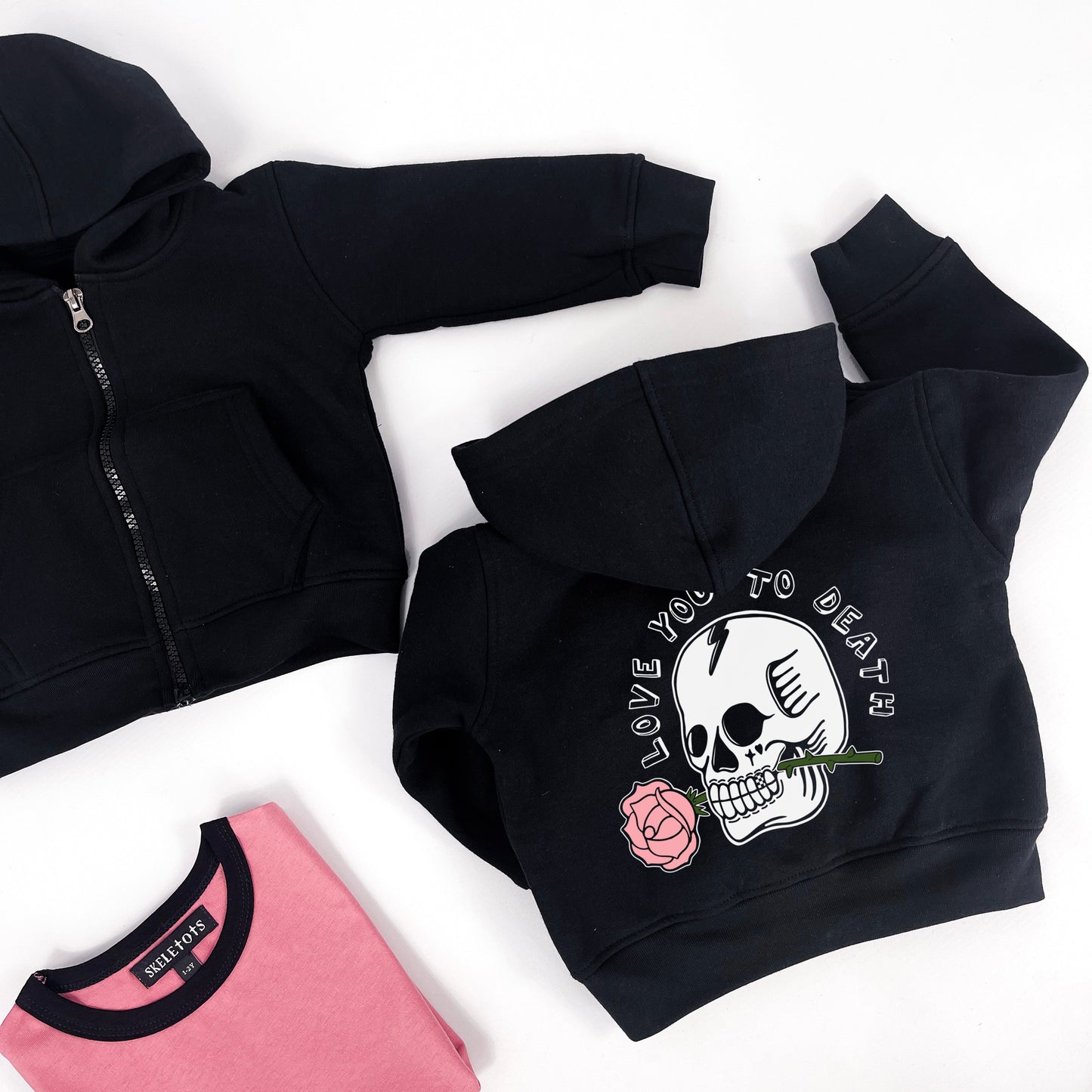 Kids black hoodie with "love you to death" printed on and a design of a skull holding a rose in its teeth