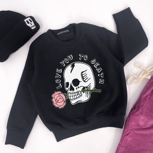 Kids black sweatshirt with "love you to death" printed on and a design of a skull holding a rose in its teeth