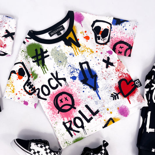Kids white tee shirt with colourful graffiti print skulls, hearts, lightning bolts and paint splatter