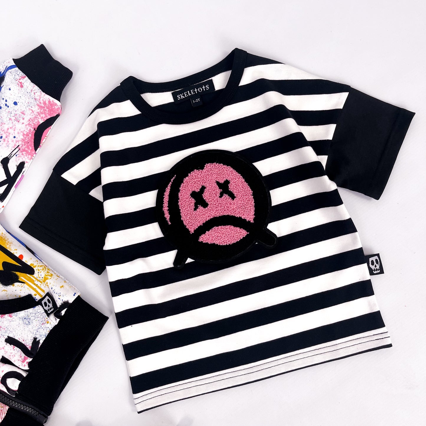 Kids black and white striped tee shirt with sad face patch