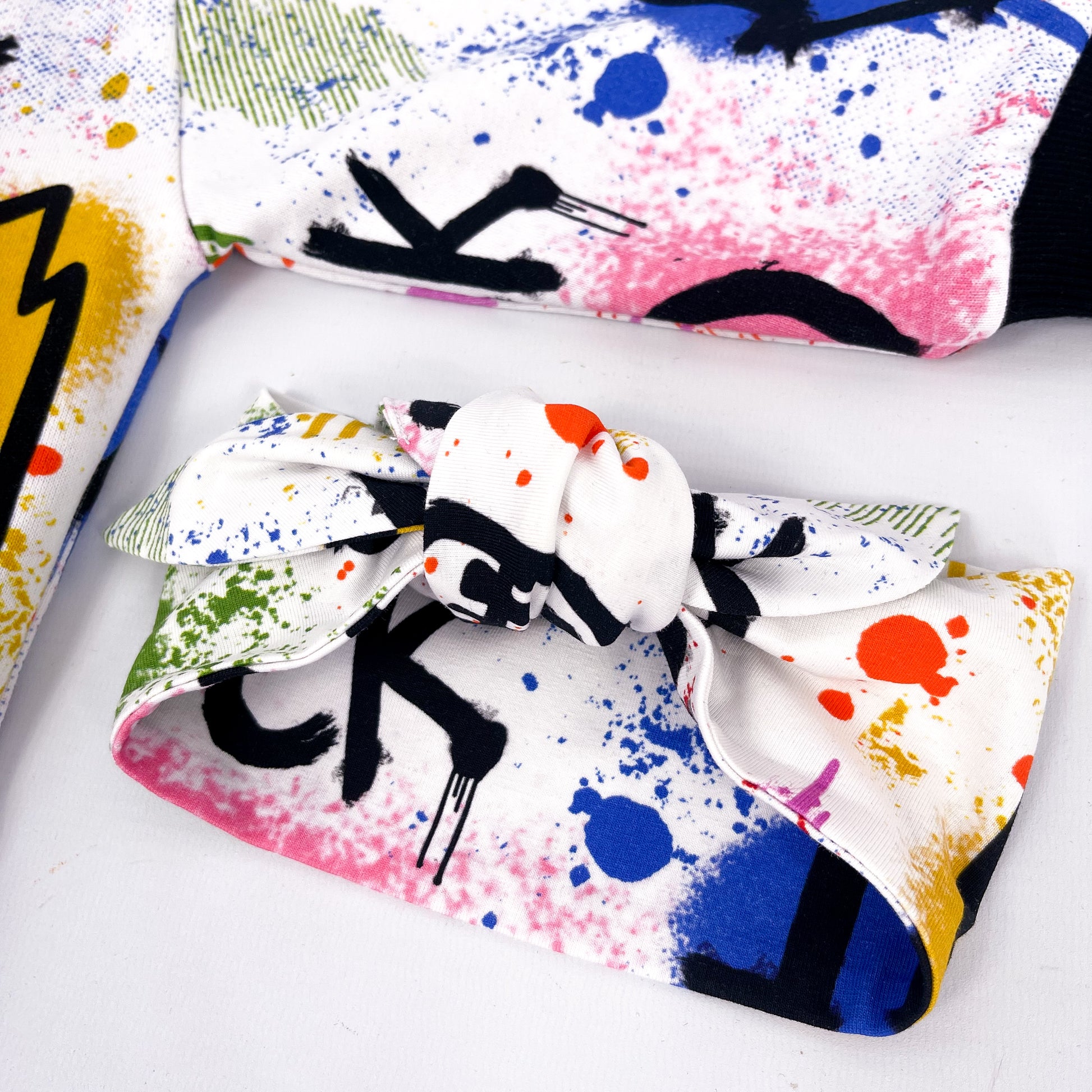 Stretchy headband with colourful paint splatter and graffiti print