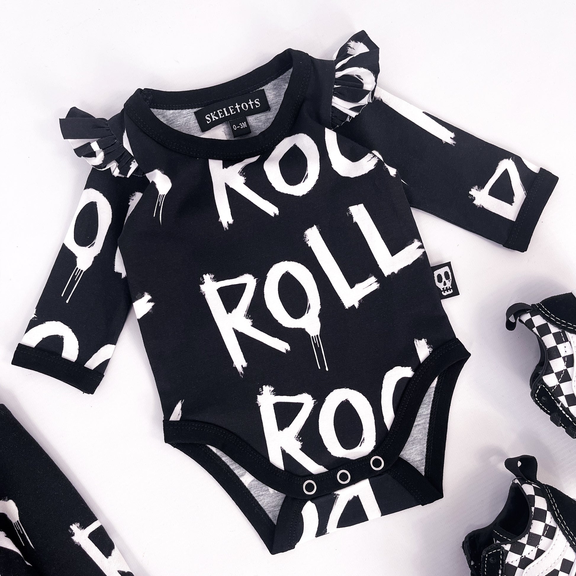 Baby's bodysuit with frilled shoulder details, pressed stud fasteners and the words "rock" and "roll" printed on
